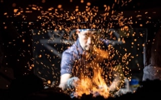 写真：火花を散らしながら金属を鍛錬する職人