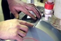 写真：機械で水をかけながら包丁を研いでいる様子